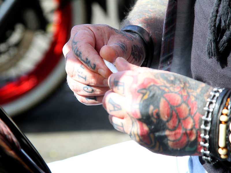 Tattooed man rolling a marijuana cigarette
