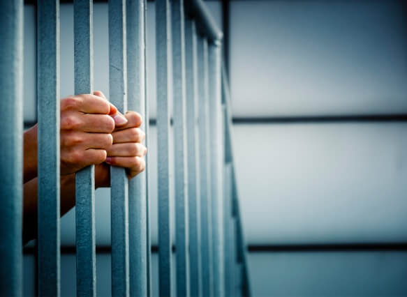 Hands grasping bars in a prison cell