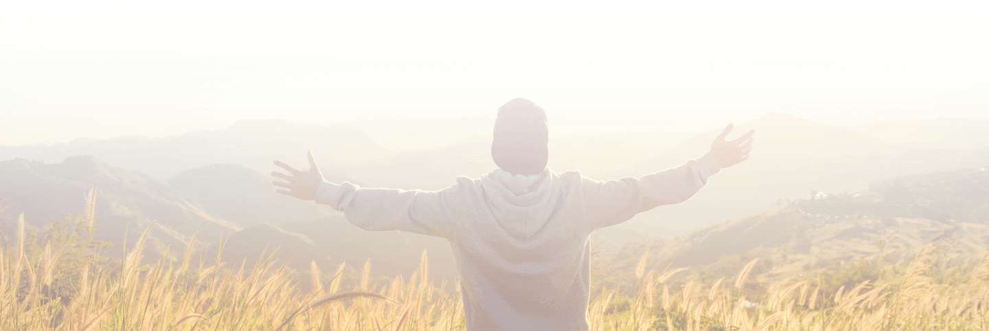 Man with arms stretched out looking out into the mountains